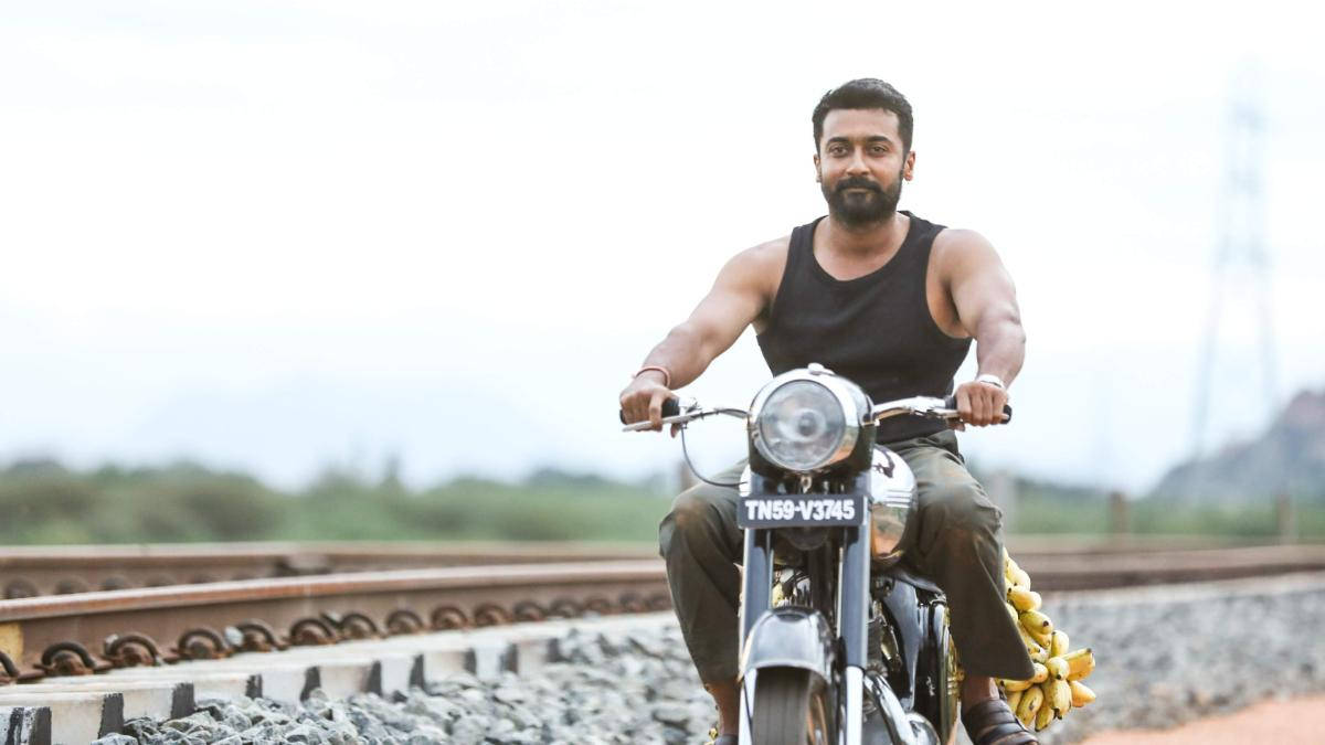Soorarai Pottru Suriya On Motorcycle Near Tracks Wallpaper