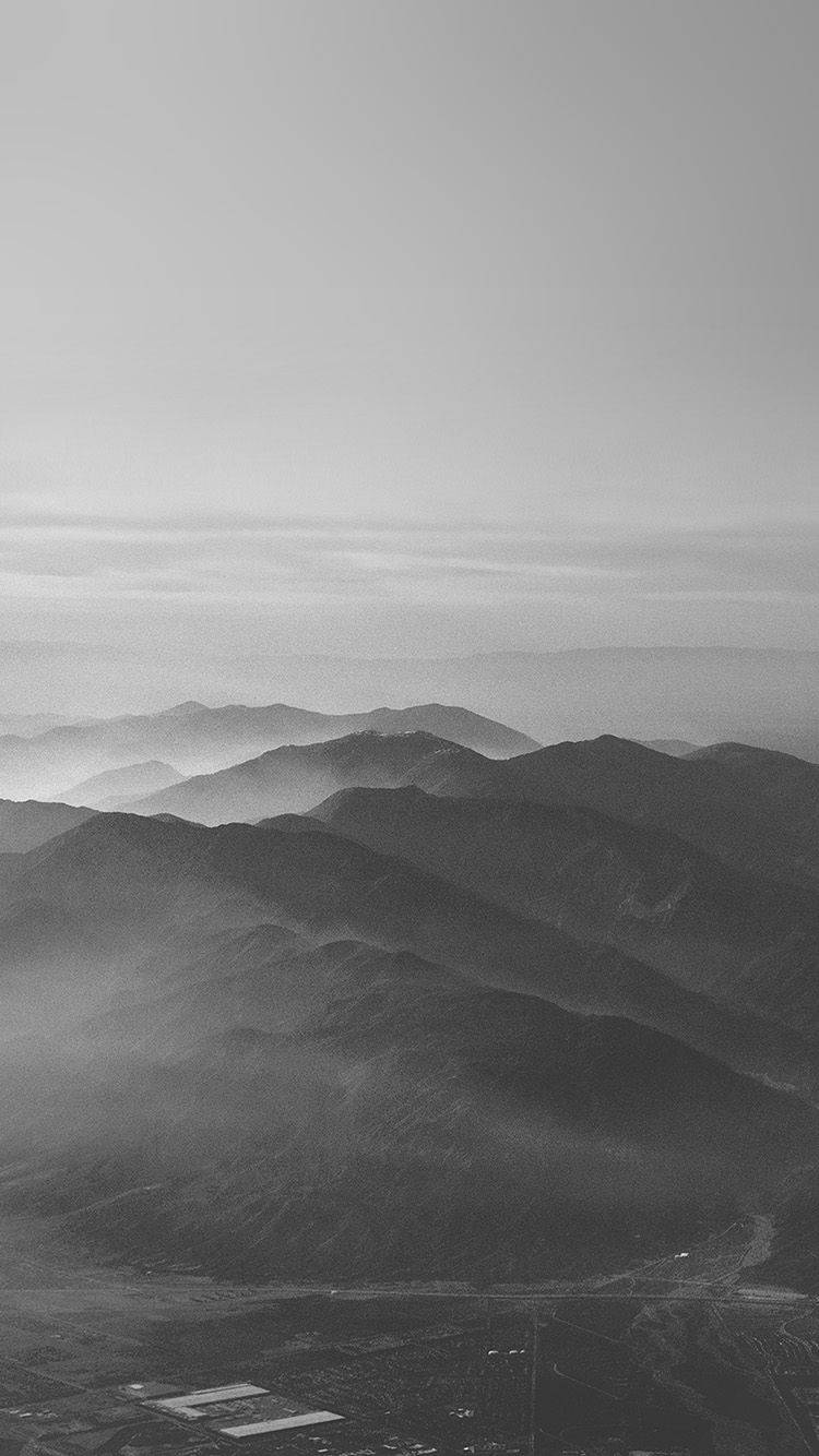 The Majestic Dark Grey Iphone Amidst Mountains Wallpaper