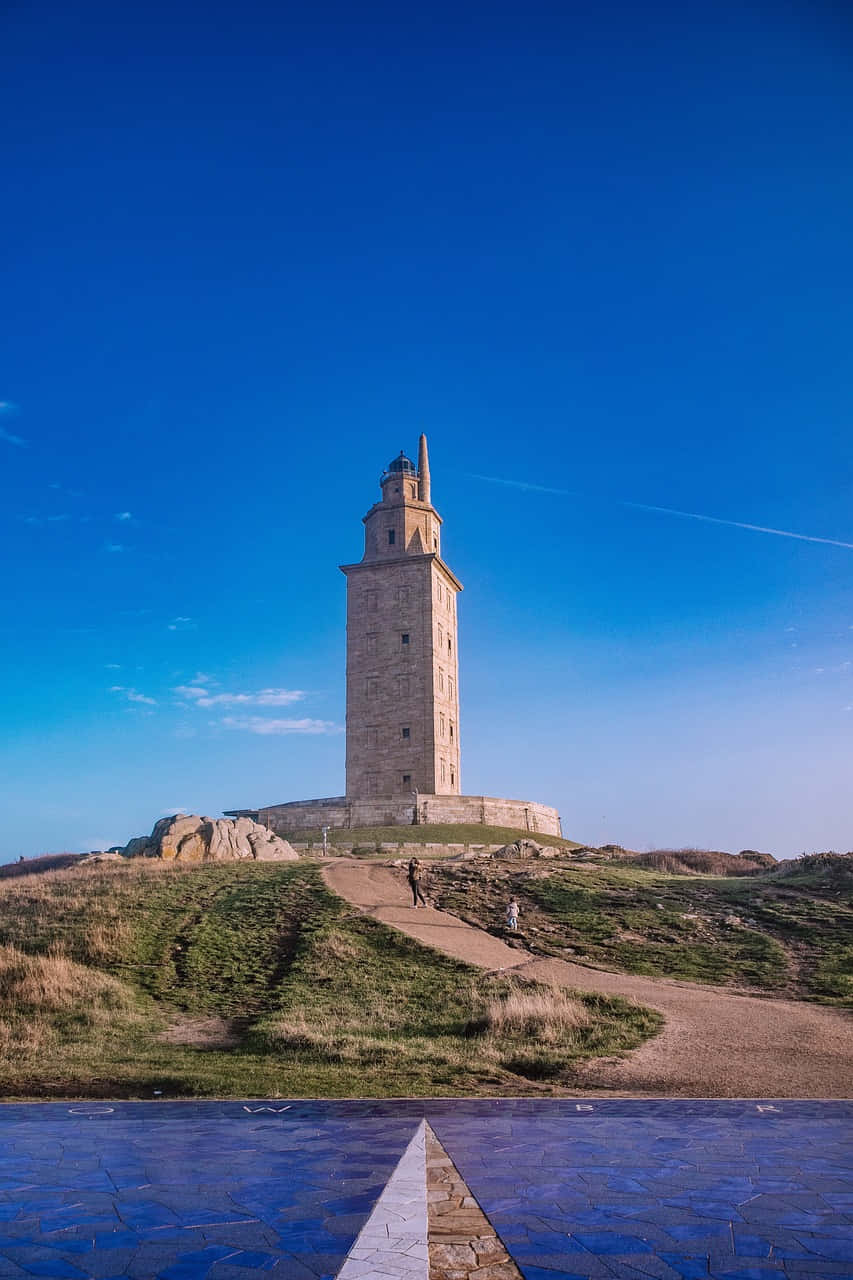 Tower Of Hercules Atop Grass Blue Aesthetic Phone Wallpaper