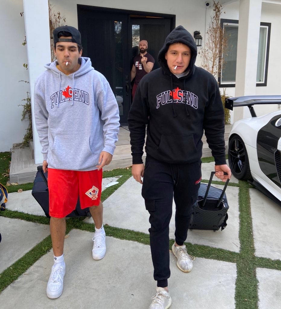 Two Men Walking With Luggage In Front Of A White Car Wallpaper