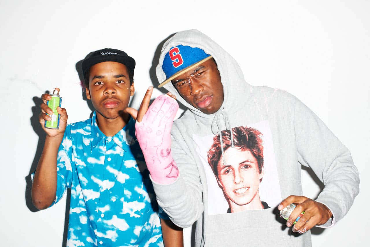 Tyler The Creator Looks Out From Behind His Laptop In A Dimly Lit Room Wallpaper
