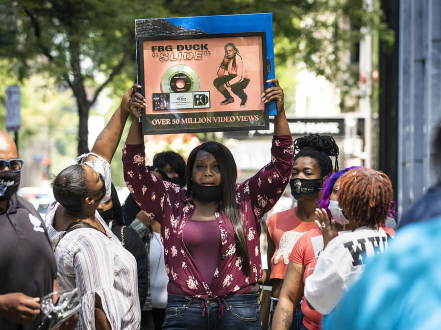 A Group Of People Holding Up A Sign In Front Of A Crowd Wallpaper