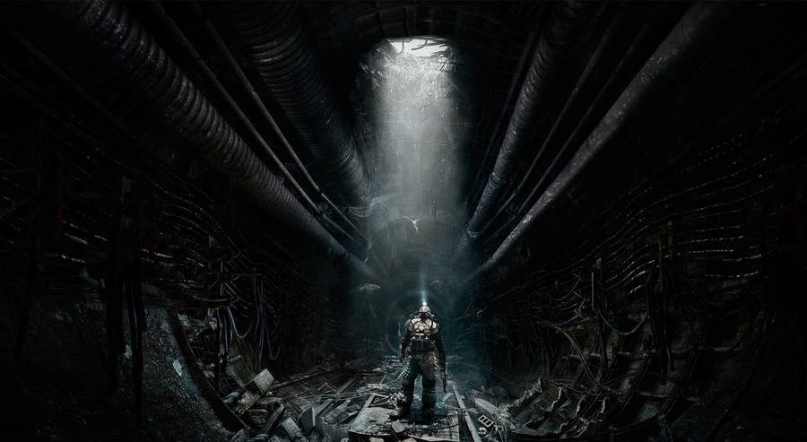 A Man Is Standing In A Dark Tunnel With A Light Shining Through Wallpaper