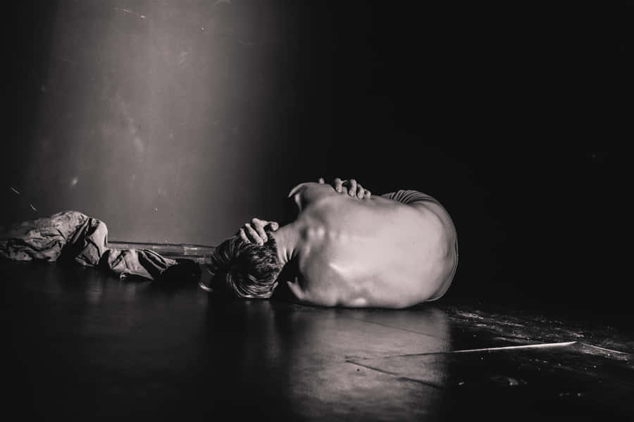 A Man Laying On The Floor With His Head Down Wallpaper