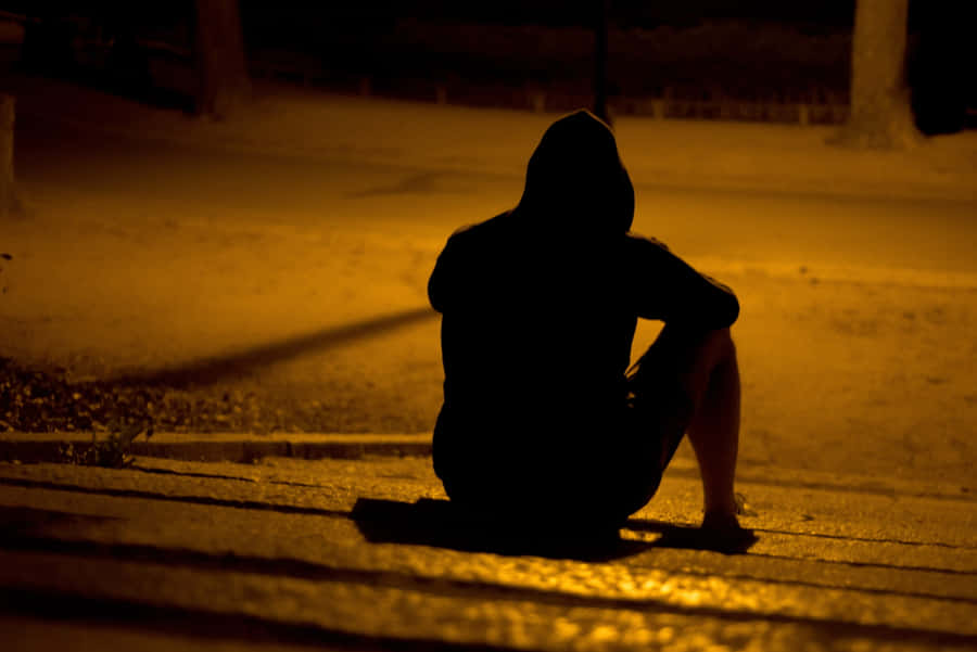 A Man Sitting On The Steps At Night Wallpaper