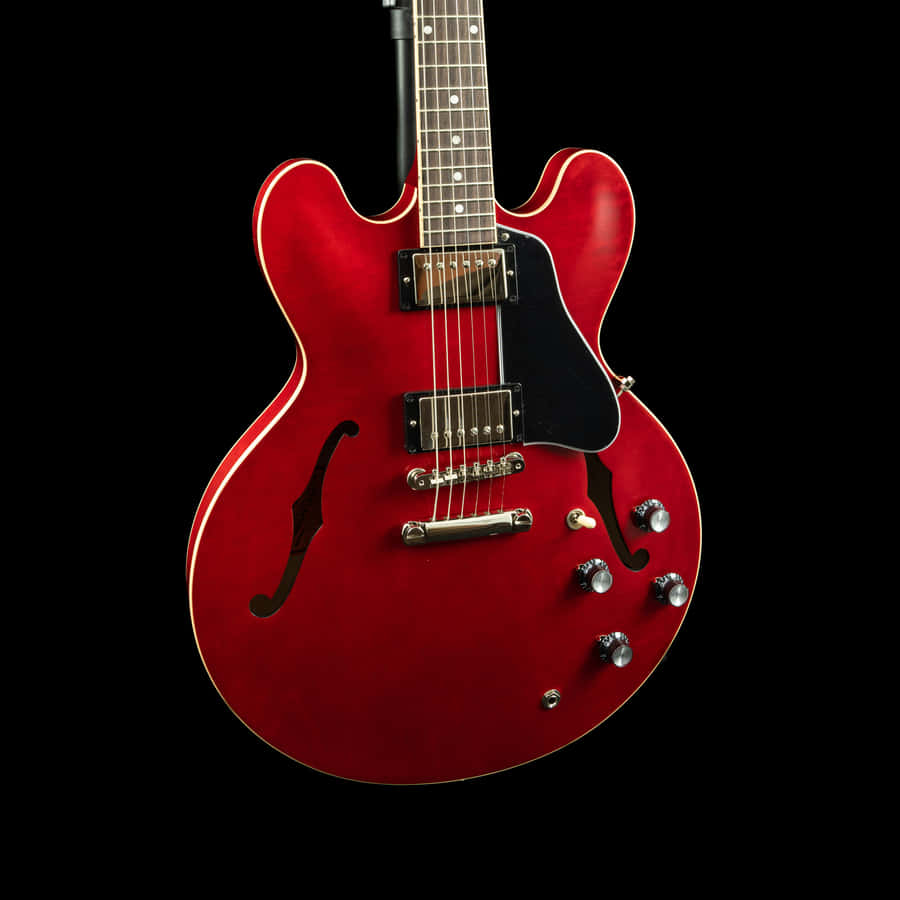 A Red Electric Guitar Is Shown Against A Black Background Wallpaper
