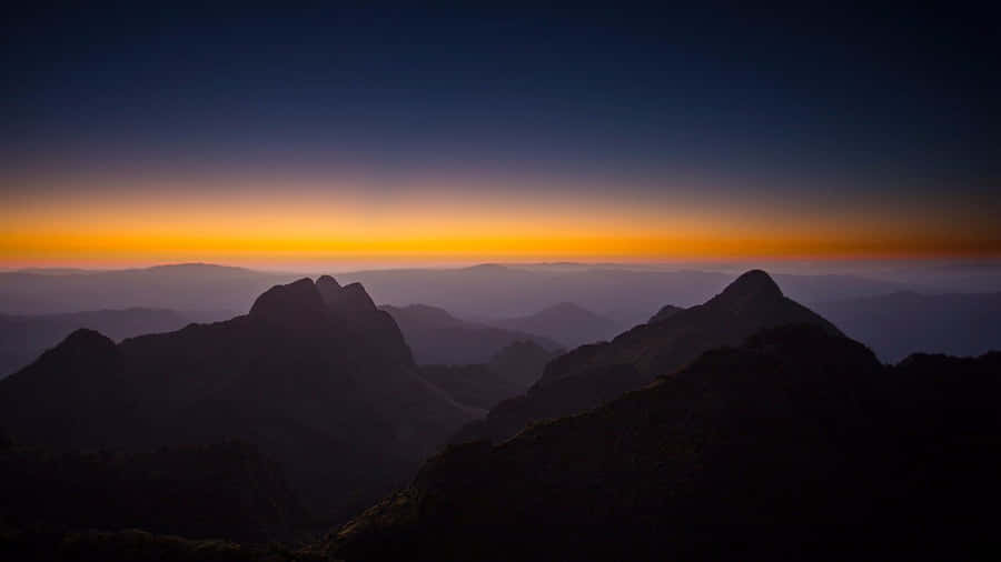 A Sunset Over Mountains With Mountains In The Background Wallpaper