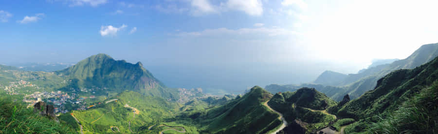 A View Of A Mountain With Green Grass And Mountains Wallpaper