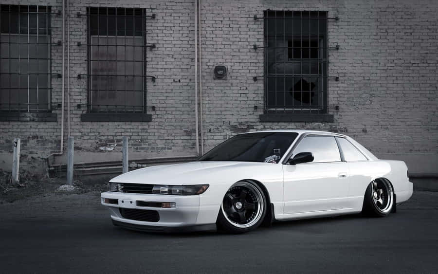 A White Car Parked In Front Of A Building Wallpaper