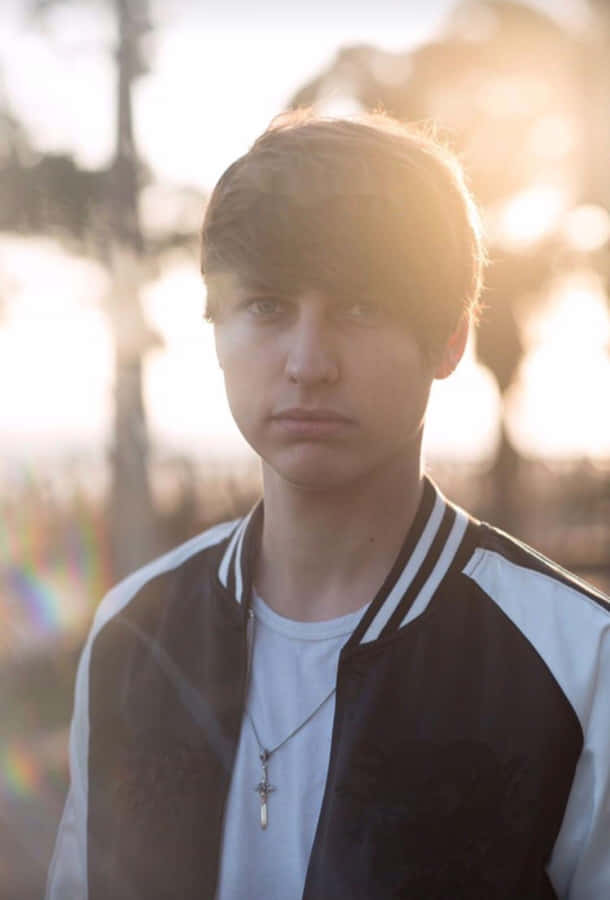 A Young Man In A Jacket Standing In The Sun Wallpaper