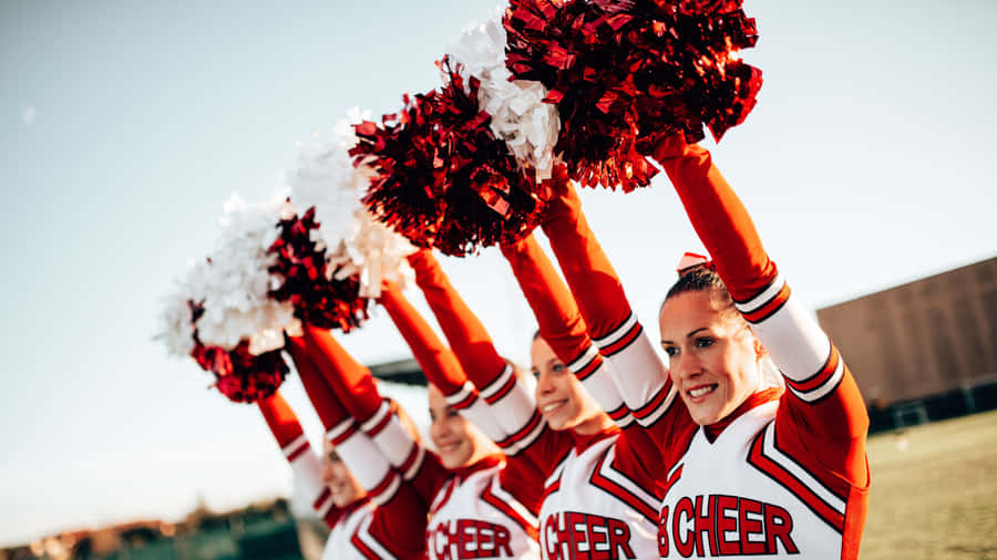 Cheerleading Squad Raising Pom Poms Wallpaper