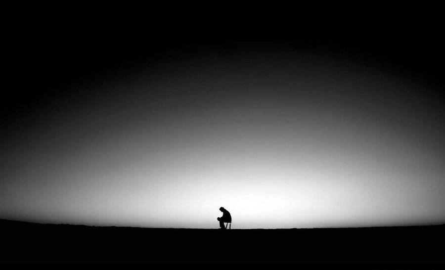 Dark Sad Man Seated On Stool Wallpaper