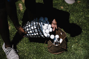 4k Person Pushing Golf Balls Towards Bag Wallpaper