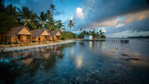 A Beach With Huts And Coconut Trees Wallpaper