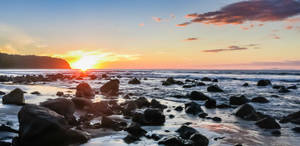 A Beach With Rocks And A Sunset Wallpaper