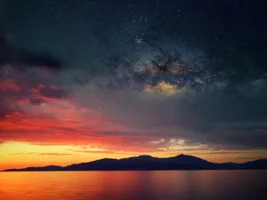 A Beautiful Sunset Over The Ocean And Mountains Wallpaper