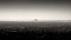 A Black And White Photo Of A City With A Mountain In The Background Wallpaper