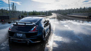 A Black Car Driving Down A Wet Road Wallpaper