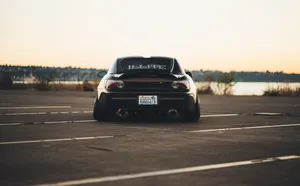 A Black Car Parked In A Parking Lot Wallpaper