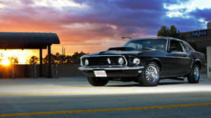 A Black Mustang Parked In A Parking Lot At Sunset Wallpaper