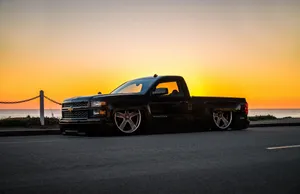 A Black Pickup Truck Parked On The Side Of The Road Wallpaper