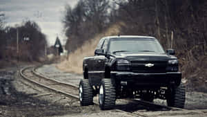 A Black Truck Driving Down A Railroad Track Wallpaper