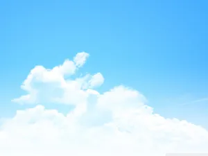 A Blue Sky With Clouds And A Plane Flying Over It Wallpaper