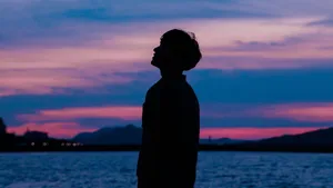 A Boy Stands Tall Against A Beautiful Purple Sky Wallpaper