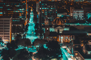 A City At Night With Buildings And Trees Wallpaper