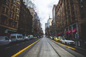 A City Street With Cars Parked On It Wallpaper