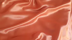 A Close Up Of An Orange Satin Fabric Wallpaper