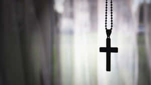 A Cross Hanging From A Curtain Wallpaper