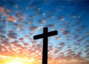 A Cross Is Silhouetted Against A Sunset Sky Wallpaper