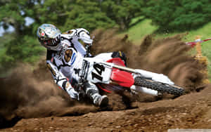 A Dirt Bike Rider Is Riding His Bike On A Dirt Track Wallpaper