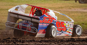 A Dirt Car Driving On A Dirt Track Wallpaper