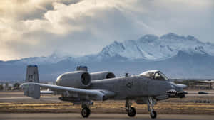 A F-16 Aaa Aircraft On The Runway With Mountains In The Background Wallpaper