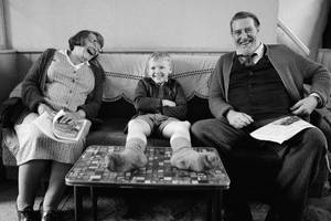 A Family Sitting On A Couch With A Young Boy Wallpaper