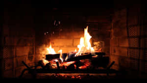 A Fireplace With Logs Burning In It Wallpaper