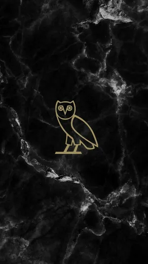 A Gold Owl Logo On A Black Marble Background Wallpaper