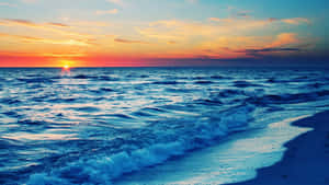 A Golden Sunset Over A Serene Beach Wallpaper