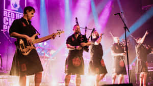 A Group Of Men In Kilts On Stage Wallpaper