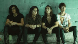 A Group Of Young Men Sitting On A Wall Wallpaper