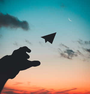 A Hand Reaching Out To A Paper Airplane Wallpaper