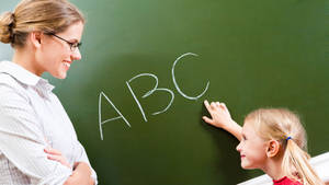 A Joyous Learning Moment: Teacher Guiding Student In Reading Alphabet. Wallpaper