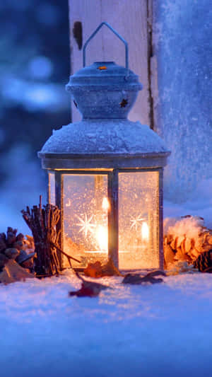 A Lantern Is Lit Up In The Snow Wallpaper