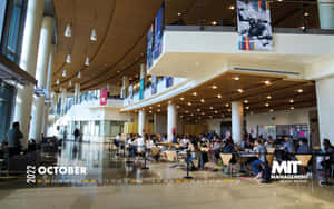 A Large Group Of People Sitting At Tables In A Large Building Wallpaper