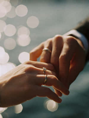 A Loving Embrace Between Husband And Wife, Featuring Their Wedding Rings Wallpaper