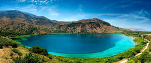 A Majestic Mountain Lake Fills Up The Horizon On A Sunny Day. Wallpaper