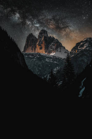 A Majestic View Of The Night Sky Over A Snow-capped Mountain Wallpaper