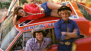 A Man And Woman Posing On The Hood Of A Car Wallpaper